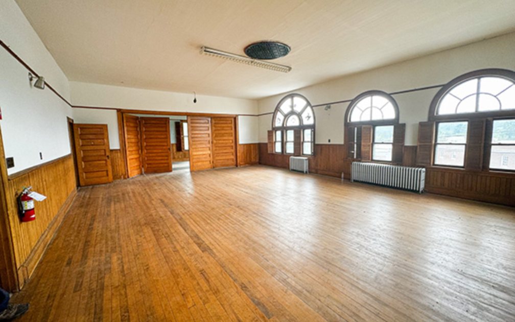 The third-floor ballroom with wood floors and arched windows